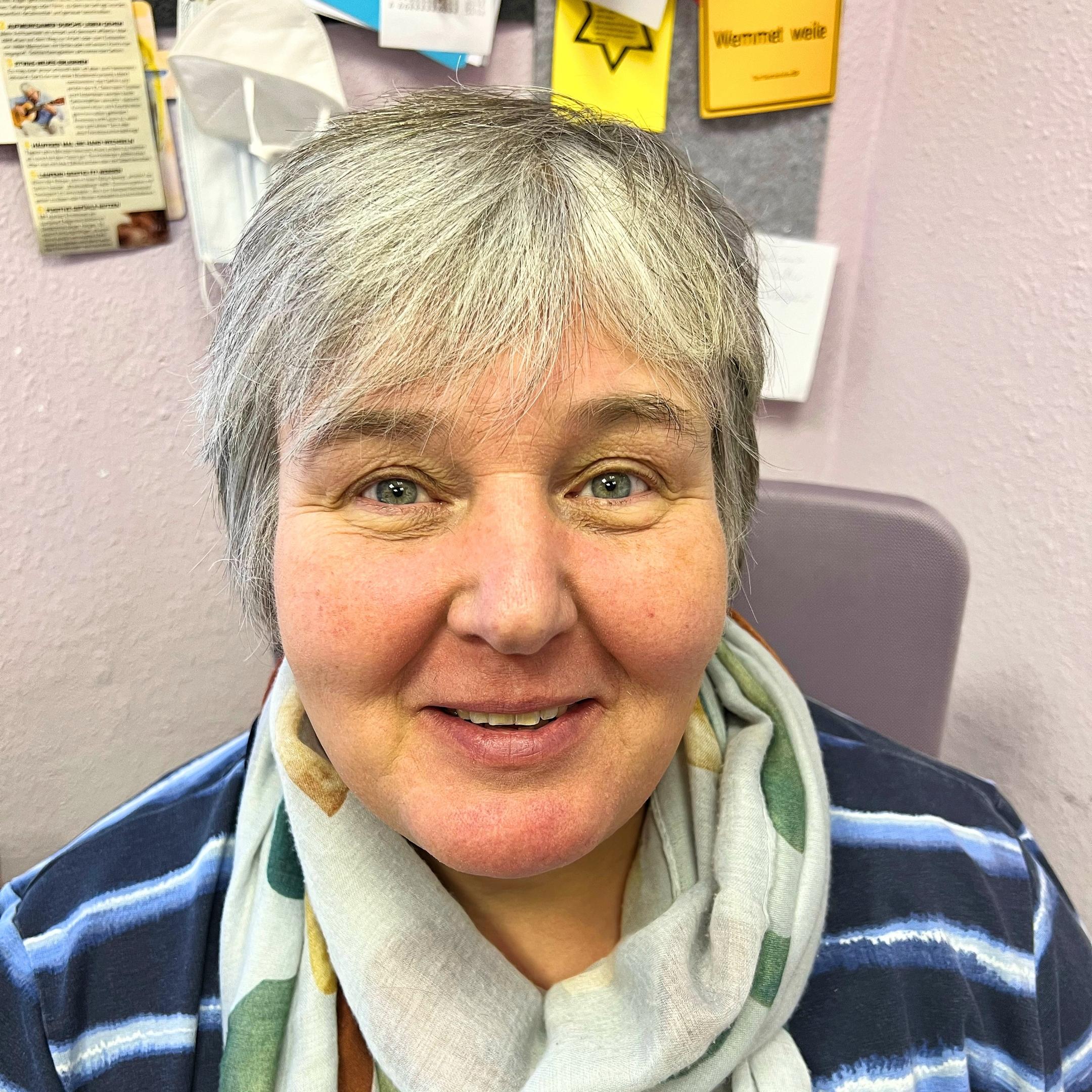 Claudia Busch mit grauen Haaren, blau gestreiftem Oberteil und hellgrauem Schal.