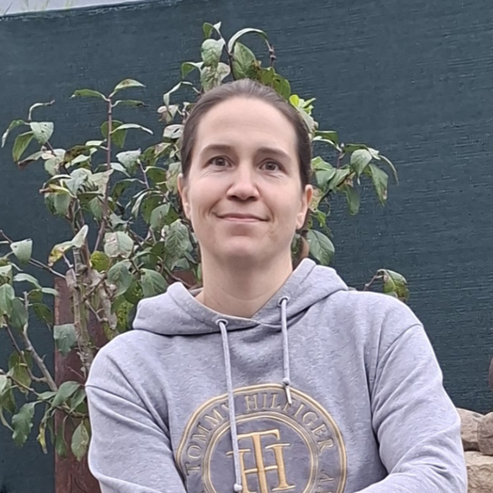 junge Frau vor einem kleinen Busch im Garten